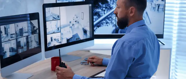 Operator watching CCTV feeds on multiple screens with a two-way radio