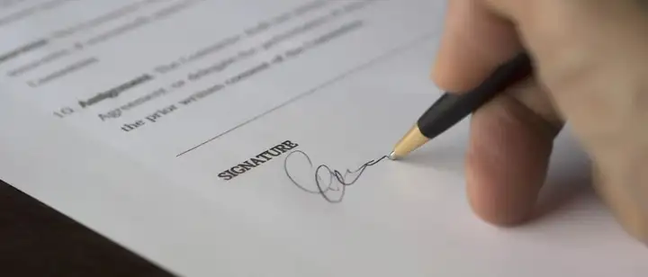 Hand signing a contract at the signature line
