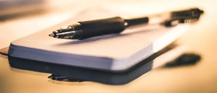Fountain pen resting on a lined pocket notebook