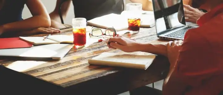 Team working together at a table with laptops and notebooks