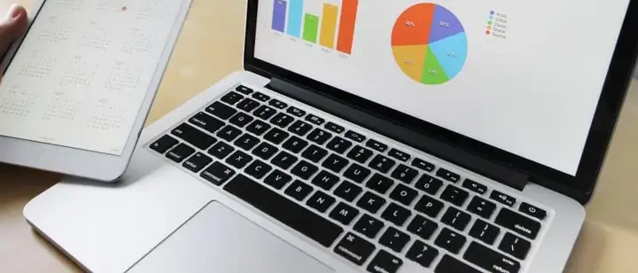 Laptop showing bar and pie charts beside a tablet calendar
