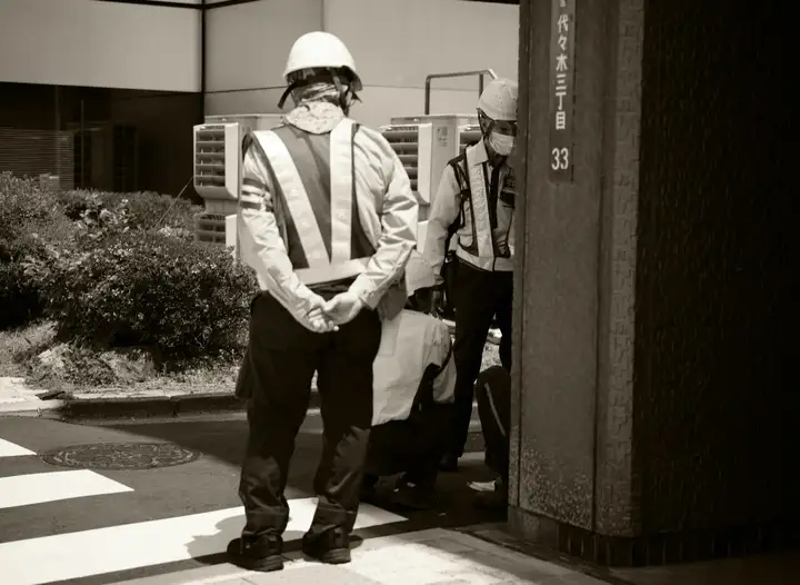 Two men in hard hats and reflective vests watching over a construction site entrance